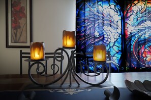 A table with three candle holders and a stained glass window in the background.
