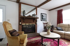 Ein Wohnzimmer mit Kamin, einer Couch, einem Sessel und einem Couchtisch.