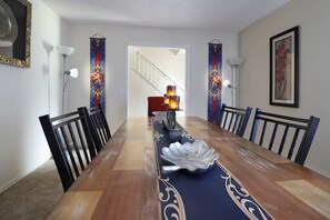 Une salle à manger avec une longue table, des chaises, un lustre et des éléments décoratifs suspendus aux murs.
