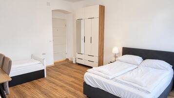 Un dormitorio moderno con cama, mesita de noche, armario y escritorio con silla.