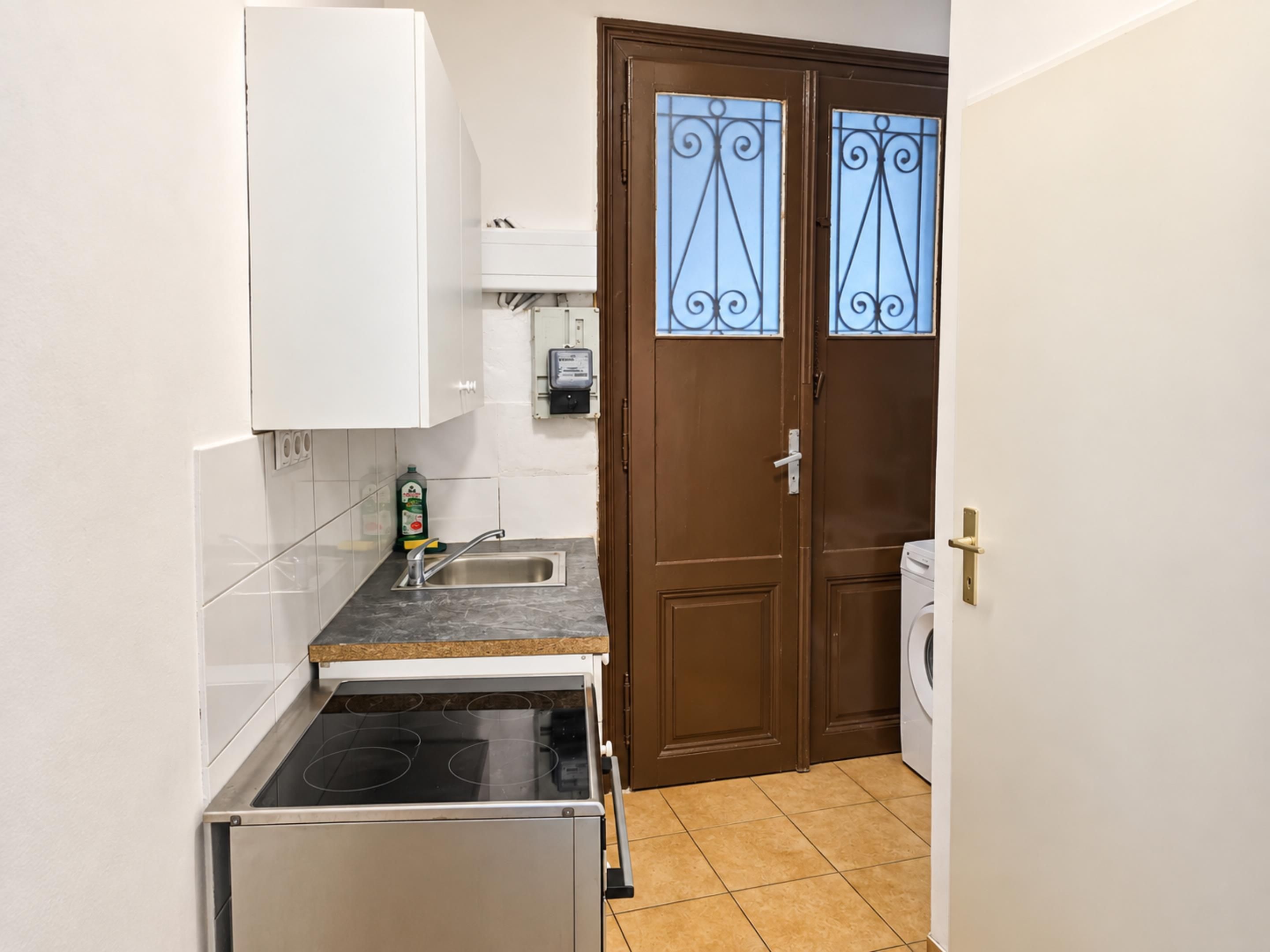 Een functionele keuken met een inbouwfornuis, een spoelbak en een wasmachine.