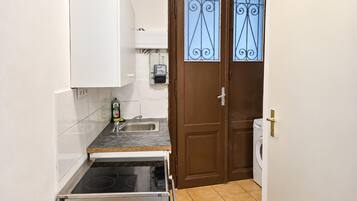 A compact kitchen with a built-in stove, a sink, and a washing machine.