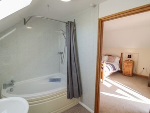 Et badeværelse med badekar, bruser og toilet.