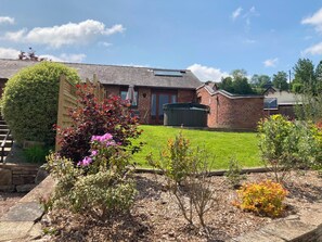 A residential property with a well-maintained lawn, a brick house, and a variety of plants and shrubs. - Pippin Bungalow (Worcester)