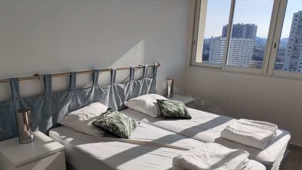 Un dormitorio con una cama, dos mesitas de noche y un ventanal con vistas a la ciudad.