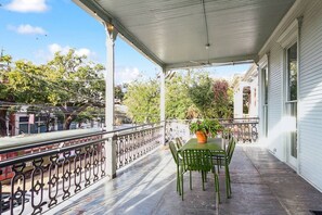 Une véranda abritée avec une table et des chaises, une plante en pot et une vue sur la rue et les bâtiments.