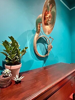 Un bagno con una parete blu, un mobile bagno in legno, uno specchio con cornice decorativa e una pianta in vaso.