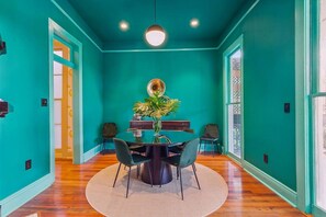 A teal-walled room with a dining table, chairs, and a large plant. - Vibrant 3BR/3BA St Charles Ave Apt w/ Balcony (New Orleans)