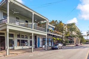 A two-story building with a balcony, a covered porch, and a street view. - Vibrant 3BR/3BA St Charles Ave Apt w/ Balcony (New Orleans)