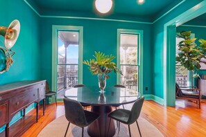 Ein raum in teal-Farbe mit einem runden Tisch, Stühlen, einer Pflanzvase und einer Wandleuchte.