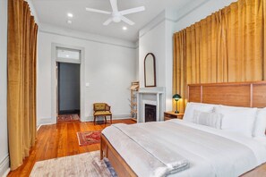Ein Hotelzimmer mit einem großen Bett, einem Kamin, einem Deckenventilator und Blick auf den Flur.