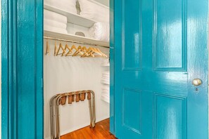 Een blauwgroene deur met een metalen radiator en een kledingrek met ophangers.