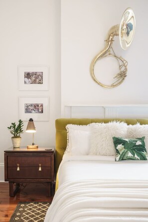 Een slaapkamer met een bed, nachtkastje, lamp en decoratie aan de muur.