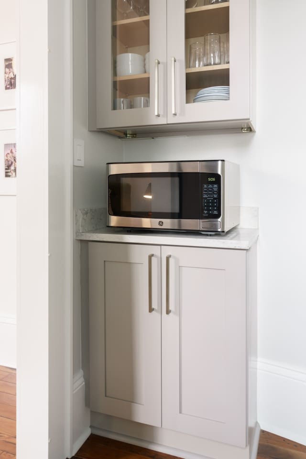 A kitchen with a microwave on top of a white cabinet.