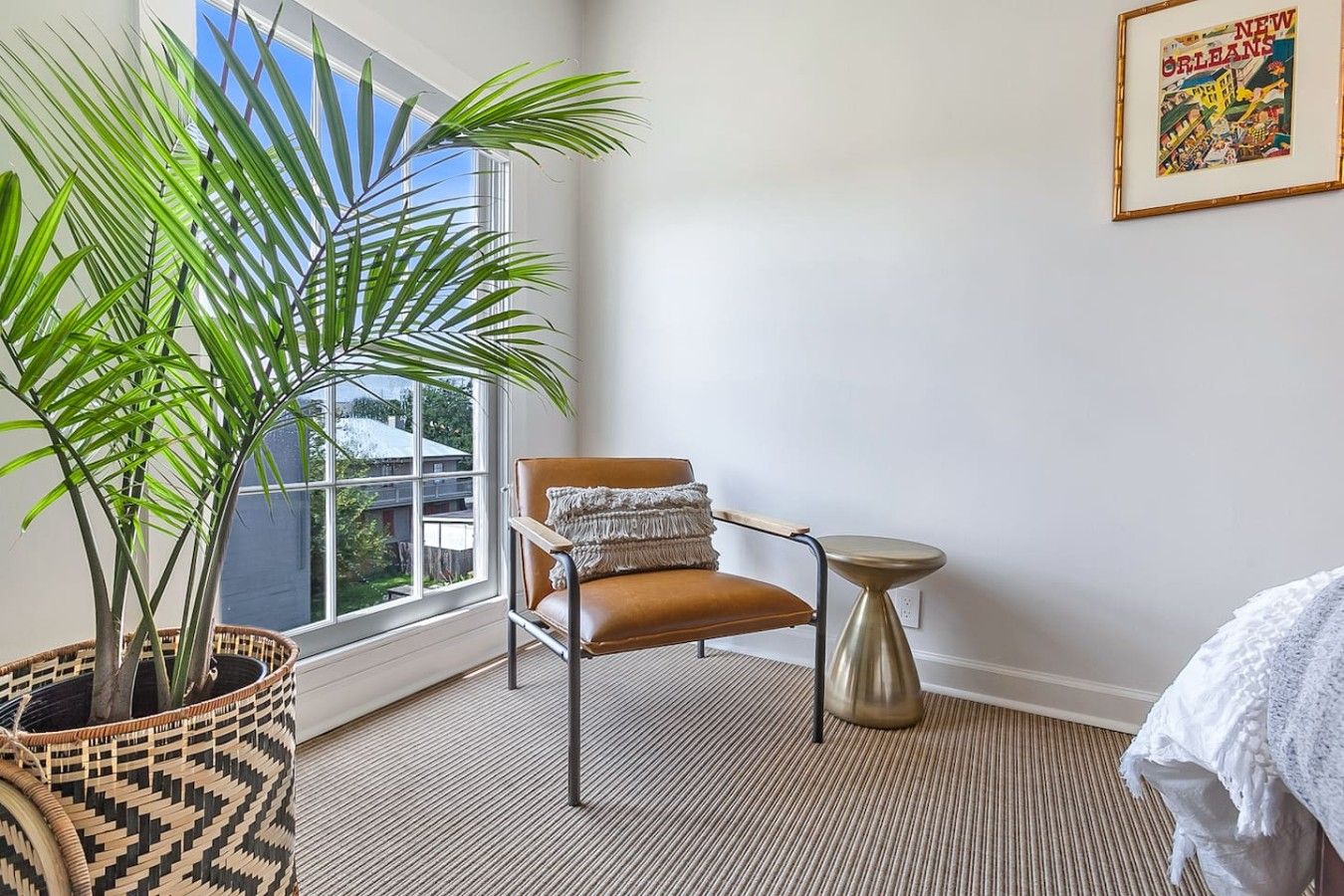 A corner room with a large window, a brown leather chair, a small round table, and a potted plant.