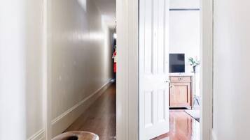 A hallway with a wooden bench, a white door leading to a kitchen, and a ceiling light fixture.
