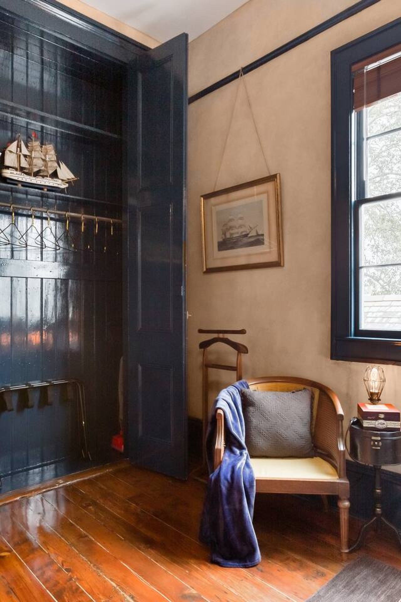 Ein Zimmer mit Holzboden, einer Bank, einem gerahmten Bild an der Wand und einem Fenster mit Blick.