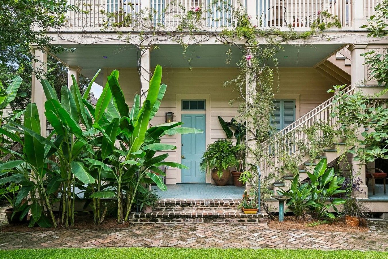 A building with a covered porch, a staircase, and various potted plants.