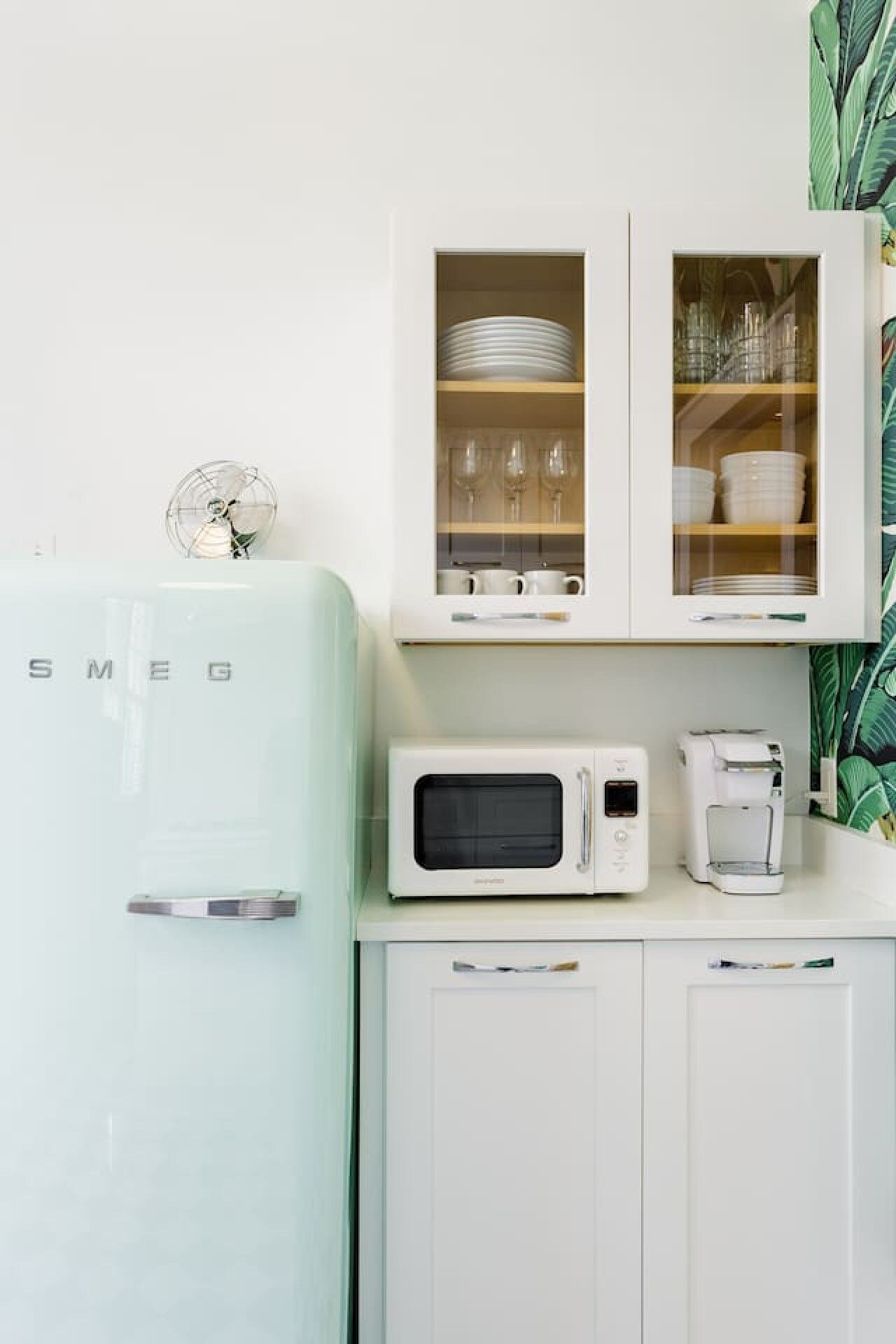 A kitchen with a vintage-style refrigerator, a microwave, and a coffee maker on the countertop.