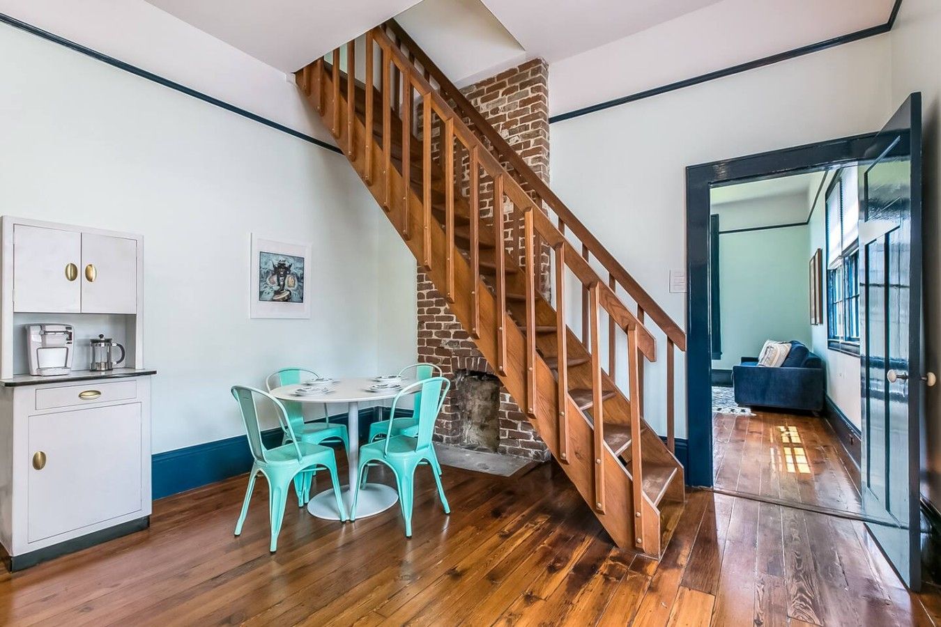 Ein Essbereich mit einer Holztreppe, eine Küche mit weißen Schränken und einer blauen Wand.