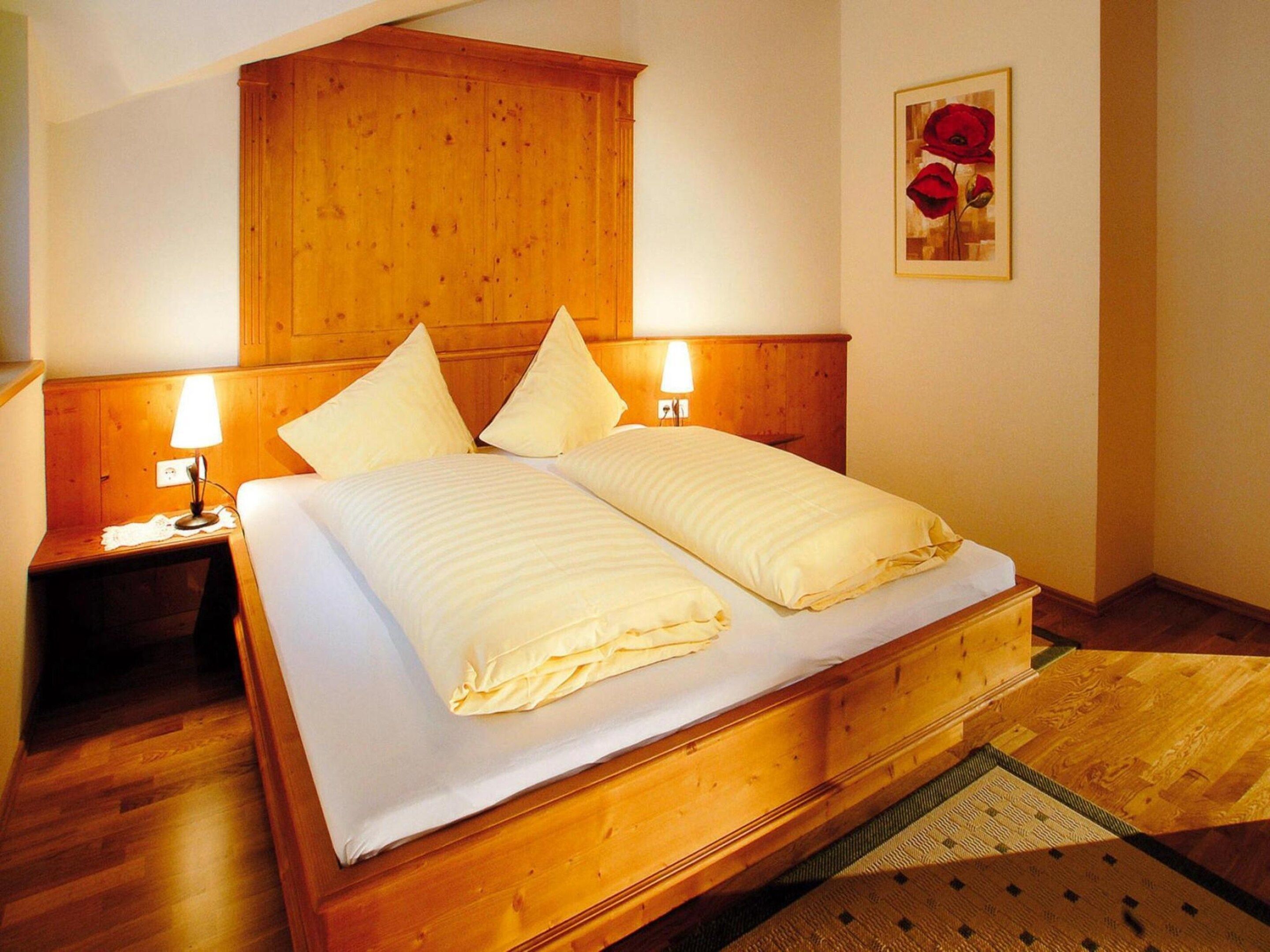 A double bed with a wooden headboard, two bedside lamps, and a framed picture on the wall.