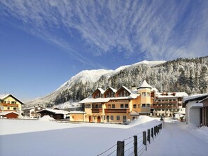 Ein schneebedecktes Gebirgshotel mit Chalets und einem klaren Himmel.