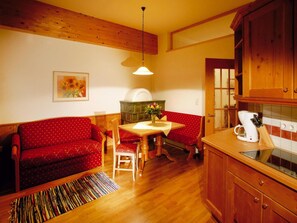 Eine gemütliche Küche mit Holzschränken, einem Esstisch mit Stühlen und einem roten Sofa.
