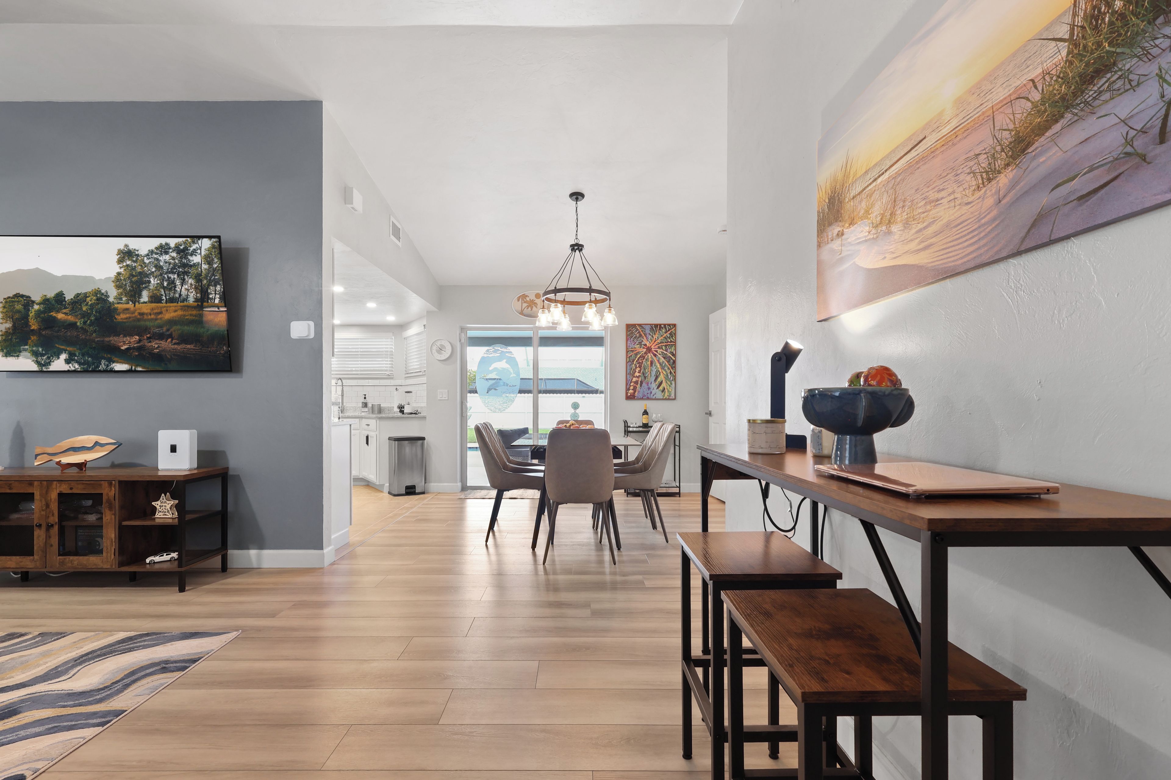 A modern living room with a dining area, wooden flooring, and a large painting on the wall.