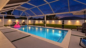 Et overdækket udendørs swimmingpool med hvidt tag, omgivet af et hvidt hegn, og med udendørsbelysning.