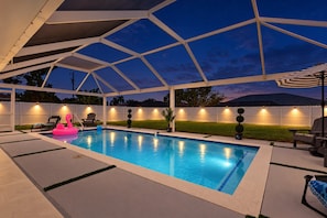 Una piscina scoperta coperta da un tetto bianco, circondata da una recinzione bianca e dotata di illuminazione esterna.