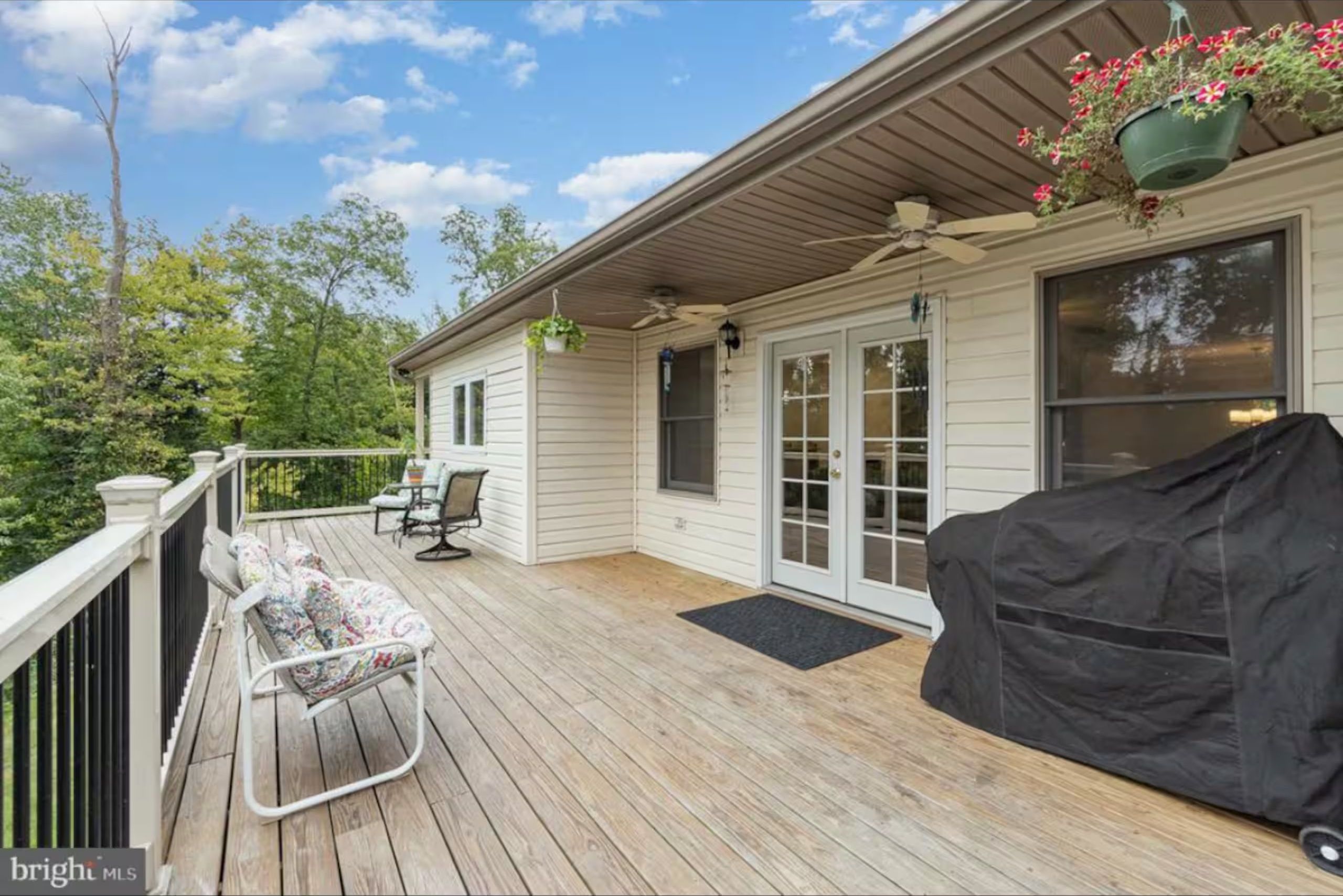 Spacious wooden back deck with outdoor seating and ceiling fans under the roof overhang.