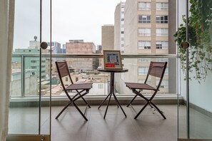 A balcony with two chairs, a small table, and a framed picture on the table. - Spacious Suite with a Balcony in Miraflores (Miraflores)