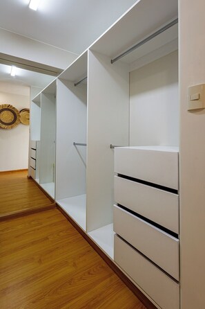 A walk-in closet with open shelving and drawers, wooden flooring, and a light switch on the wall. - Spacious Suite with a Balcony in Miraflores (Miraflores)