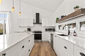 Eine moderne Küche mit weißen Schränken, einem Edelstahlherd, einer Mikrowelle und einem eingebauten Backofen.