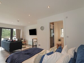 A modern bedroom with a large bed, a TV, and a view of the outdoors. - Broomfield Hideaway (Inverness)