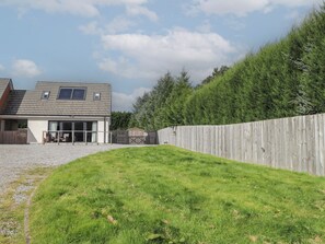 A residential property with a house, a fenced yard, and a dense forest in the background. - Broomfield Hideaway (Inverness)
