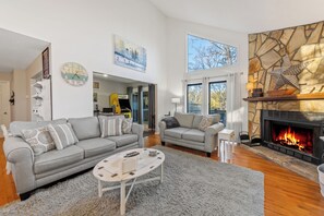 Ein modernes Wohnzimmer mit Kamin, einem grauen Sofa, einem Couchtisch und einer Wand aus Naturstein.