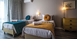Una camera d'albergo con due letti, un comodino, una lampada e un quadro appeso al muro.