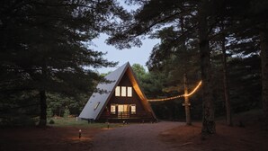 A cabin with a sloped roof, large windows, and a porch. - Cozy A-frame w/HOT TUB, 5min walk to lake, King Bed, 30 min to Dells (Friendship)