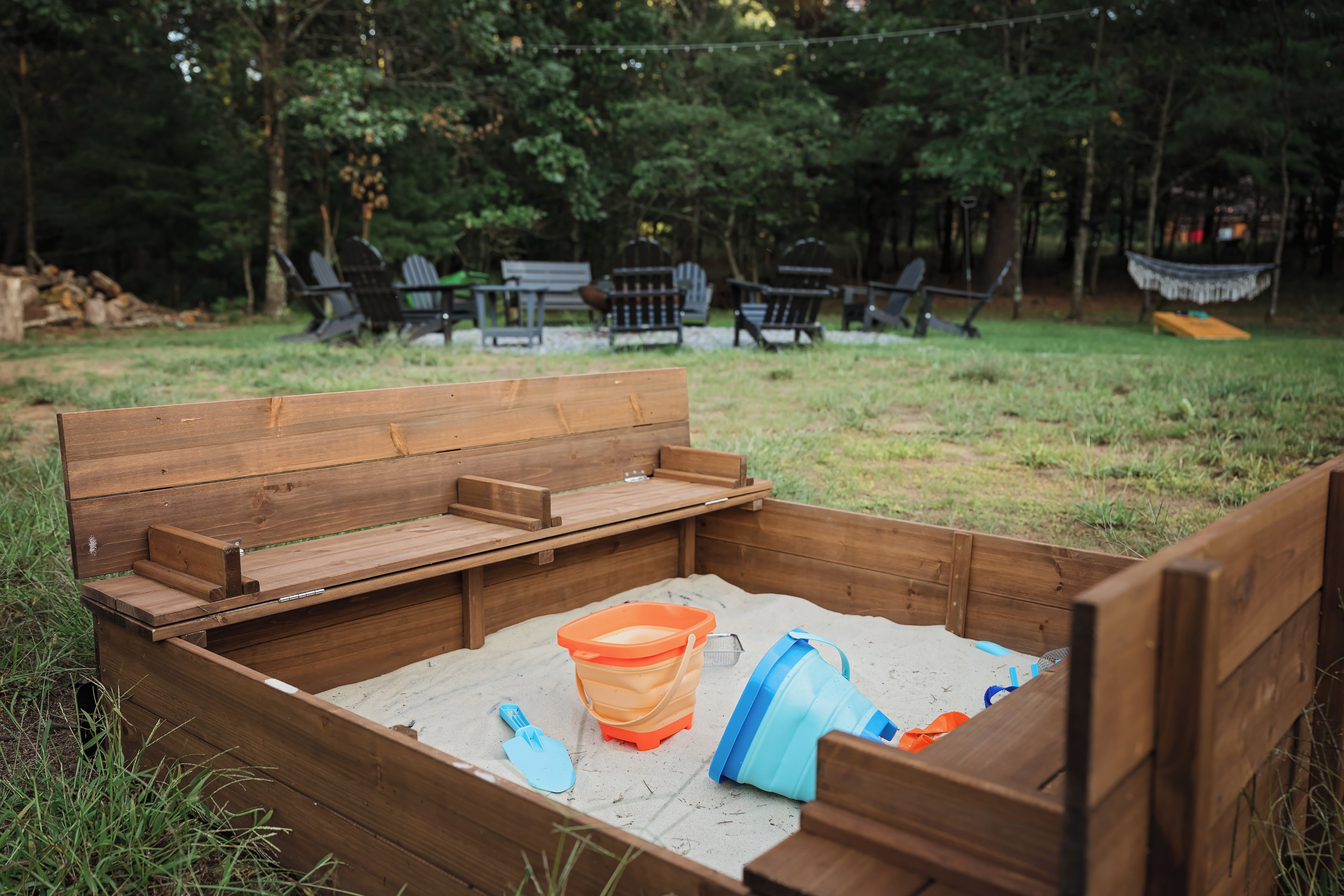 A wooden bench with a built-in storage compartment containing a shovel and a plastic container.