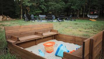 A wooden bench with a built-in storage compartment containing a shovel and a plastic container.