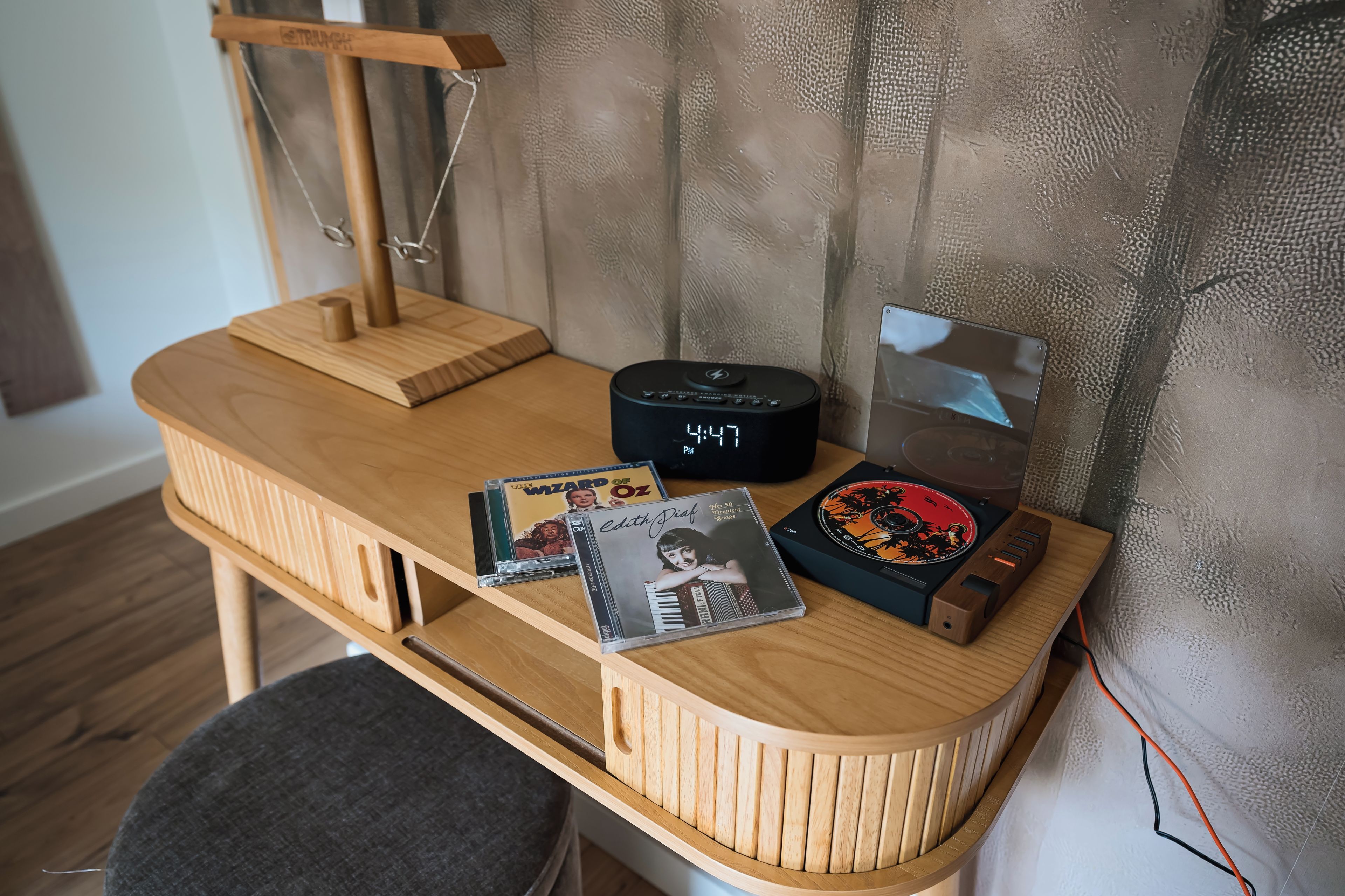 Un escritorio de madera con un reloj, un altavoz y dos CDs.