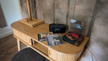 Un escritorio de madera con un reloj, un altavoz y dos CDs.