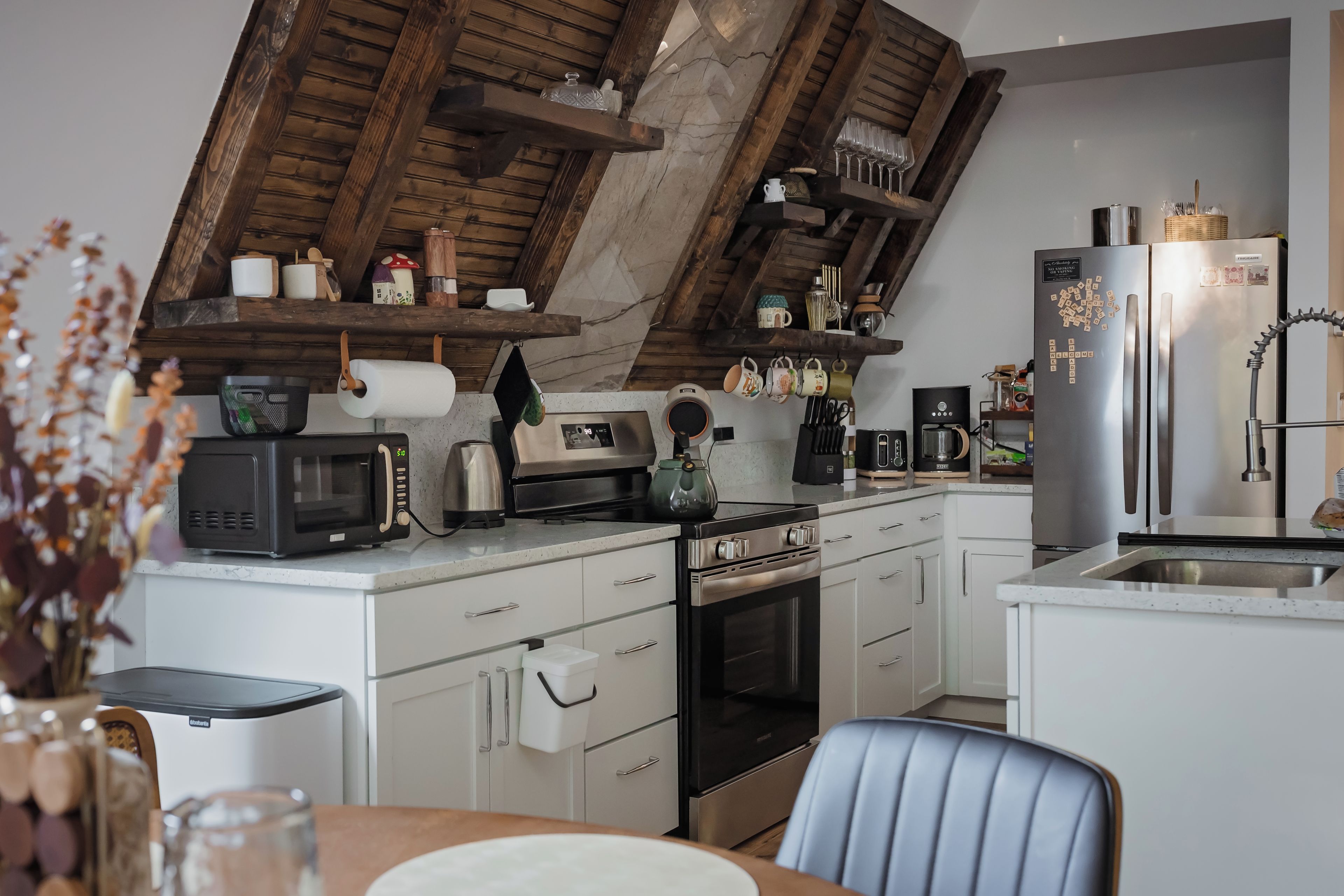 Een moderne keuken met een ingebouwde oven, magnetron en een roestvrijstalen koelkast.