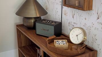 Una estantería de madera con una lámpara, un radio, un reloj y un bolso de cuero.