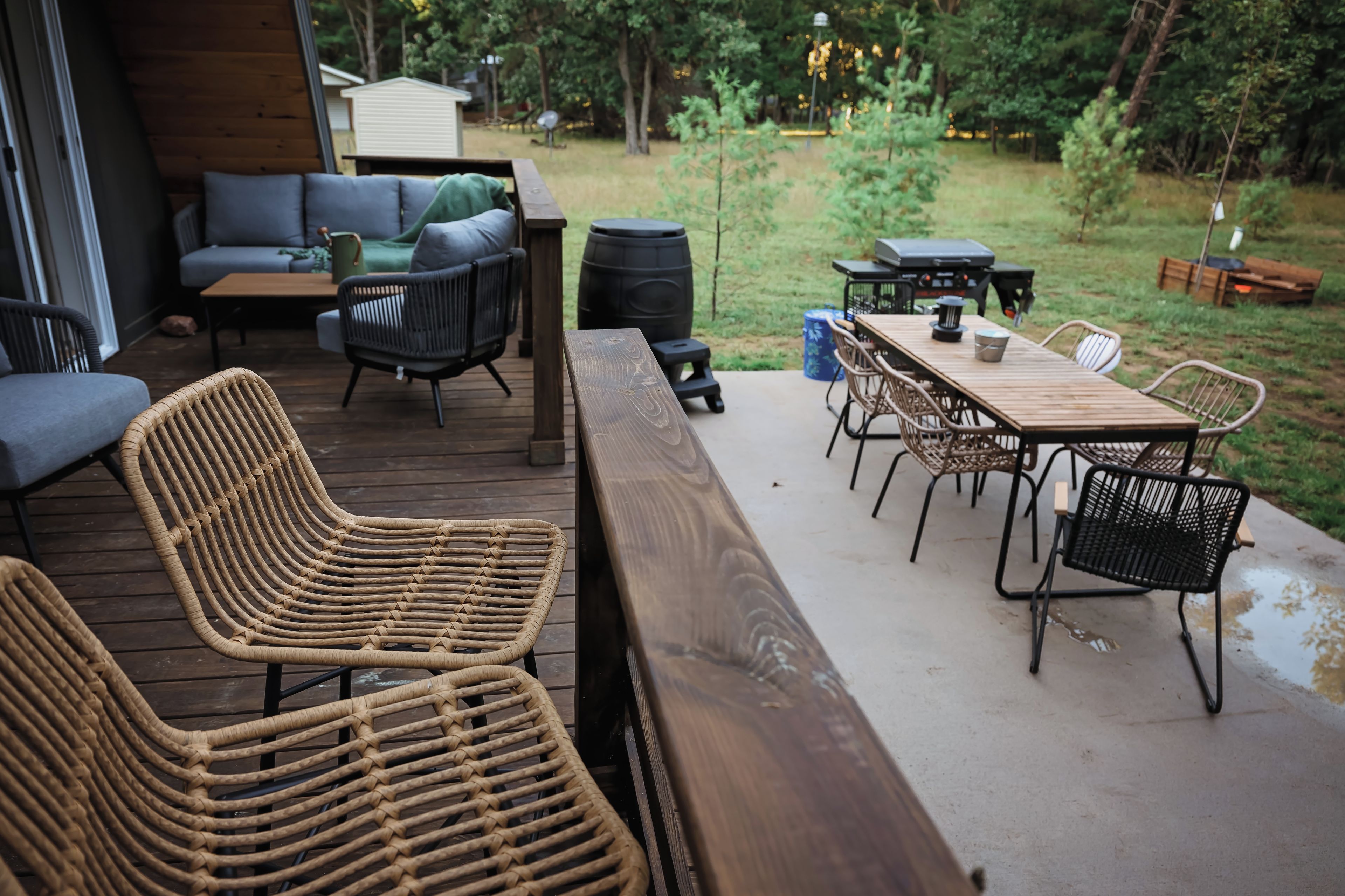 An outdoor patio with wicker furniture, a wooden table, and a grill.