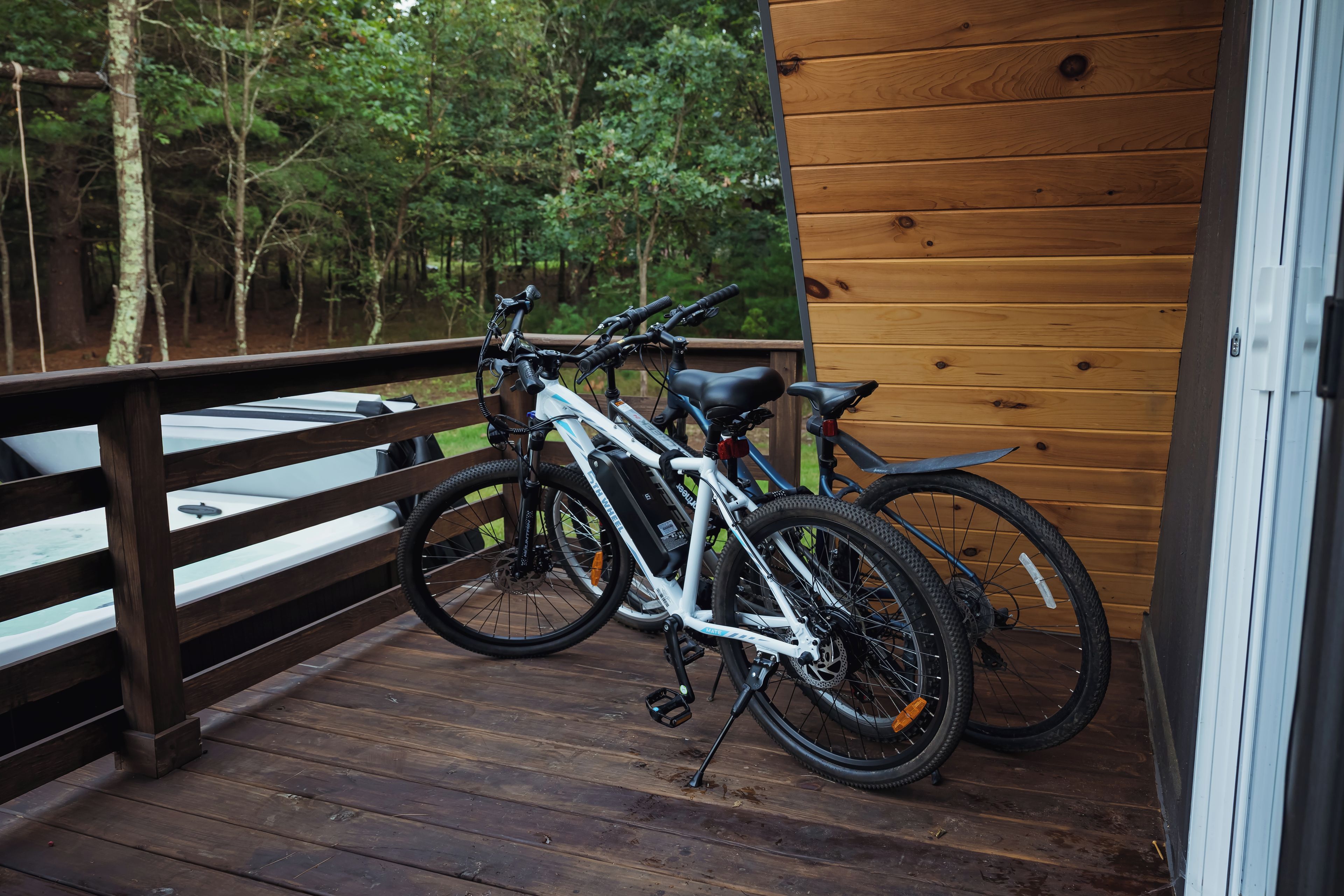 A wooden deck with two bicycles parked, overlooking a forested area.