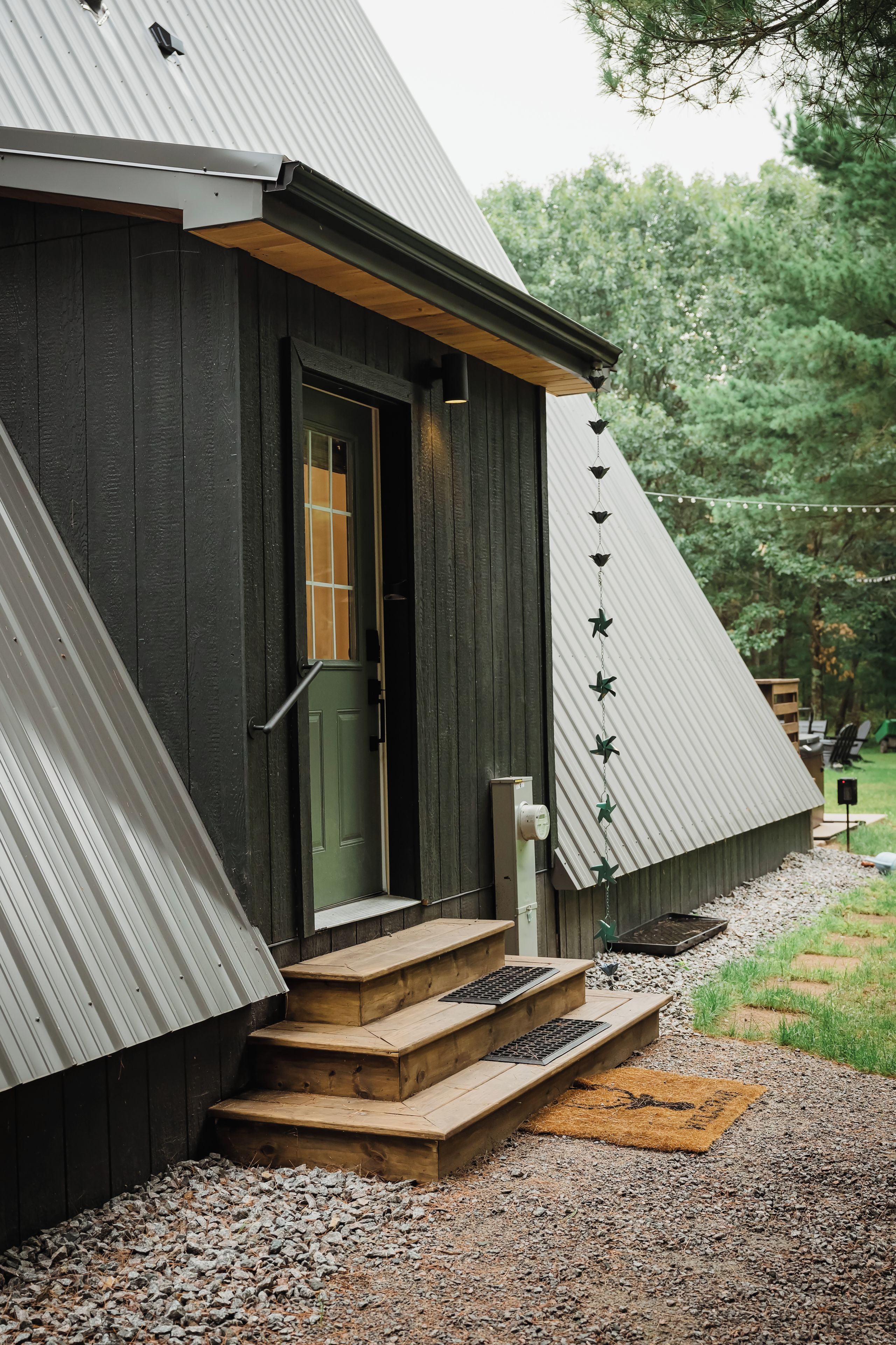 A rustic wooden building with a green door, a small porch with steps, and a metal roof.