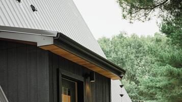 A rustic wooden building with a green door, a small porch with steps, and a metal roof.