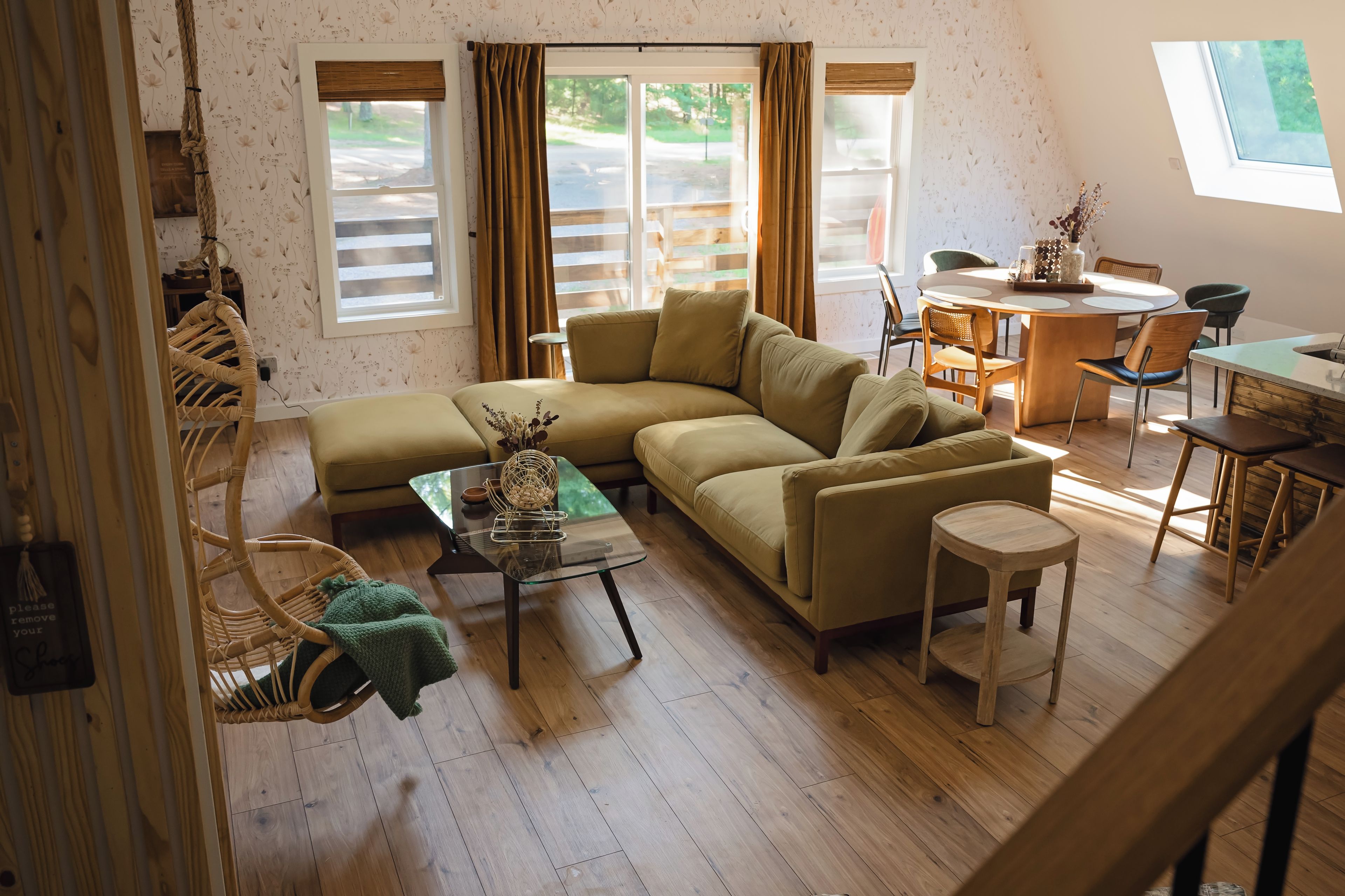 A cozy living room with a sectional sofa, a glass coffee table, and a dining area with a round table and chairs.